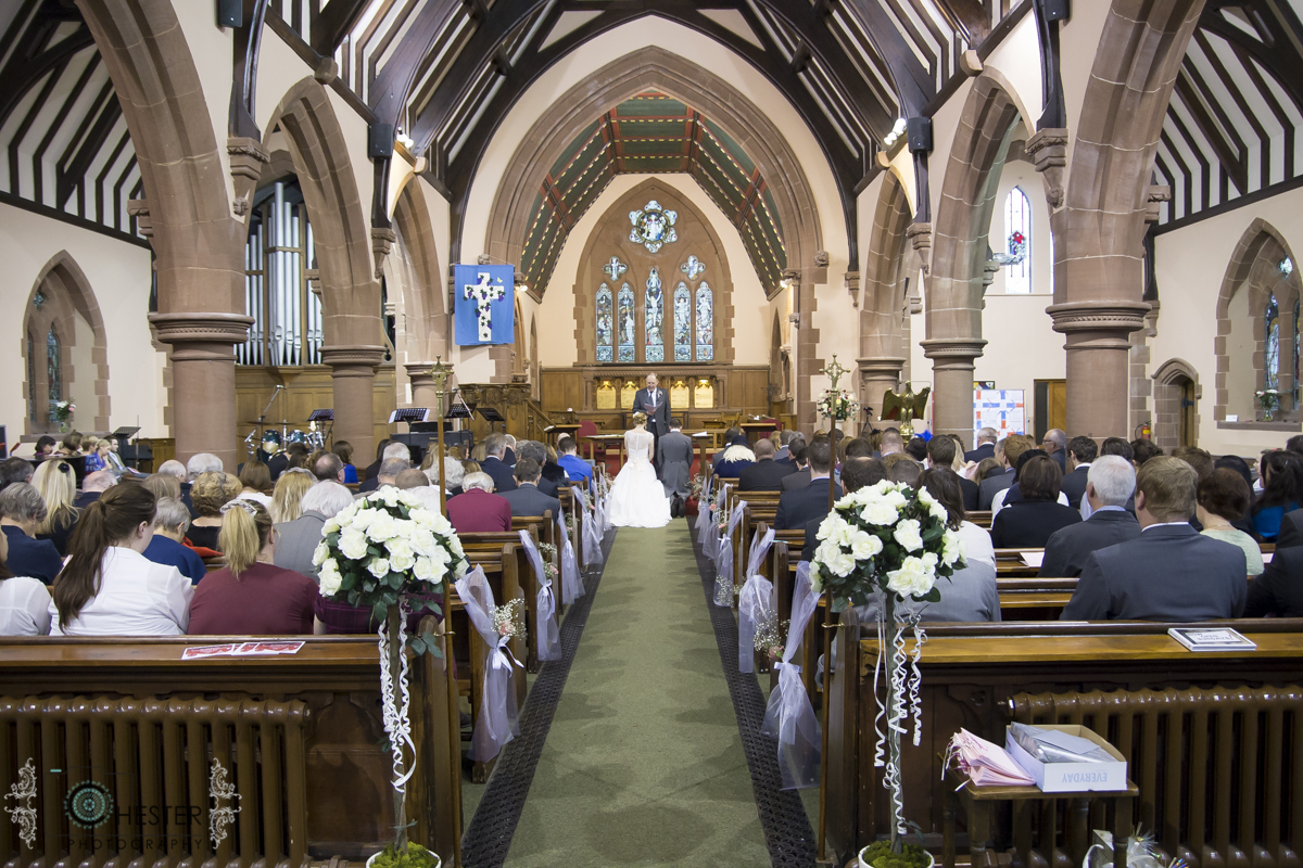 The inside of All Saints Church at a wedding (flowers, people sitting in pews, bride and groom at the front)
